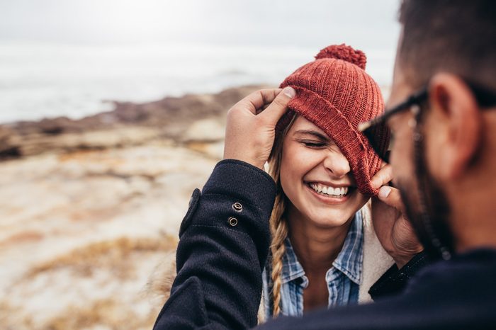 Close up portrait of smiling young couple having fun outdoors. Man and woman enjoying themselves on a winter day at the beach.