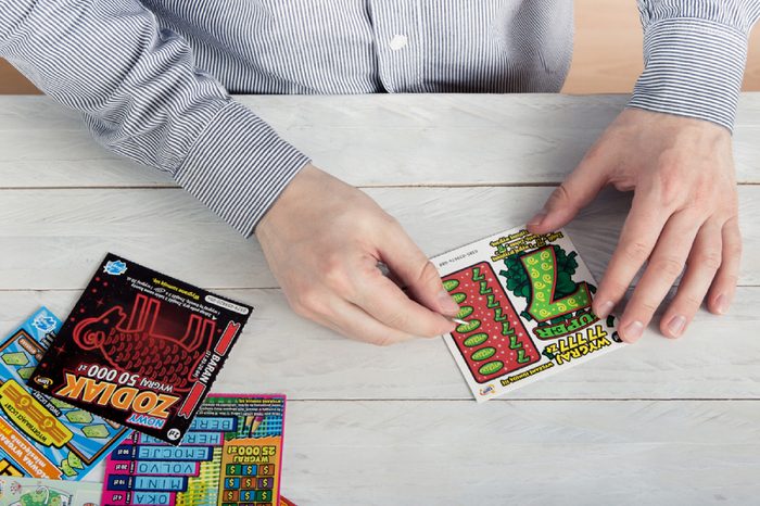 WROCLAW, POLAND - MARCH 28th, 2017: Man scratches Polish lottery scratchcard. Scratchcard is a small card, where areas contain concealed information which can be revealed by scratching off.