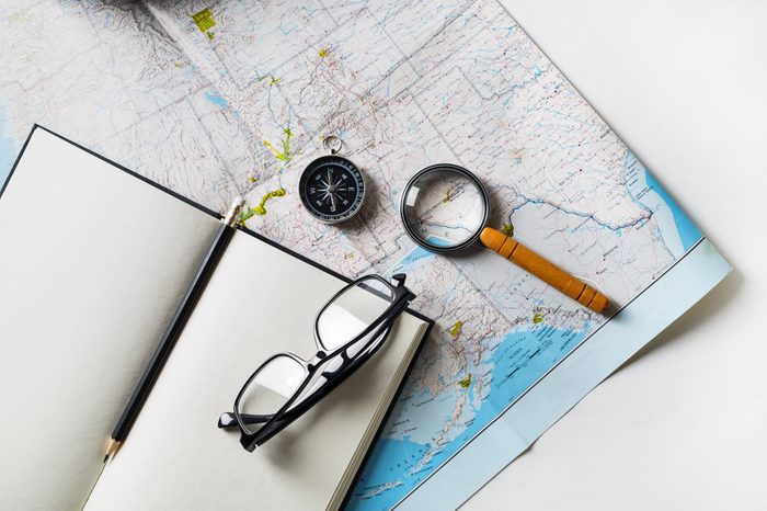 Travel plan background. Ready for the trip. Map, blank notebook, magnifier, compass, glasses and pencil. Flat lay