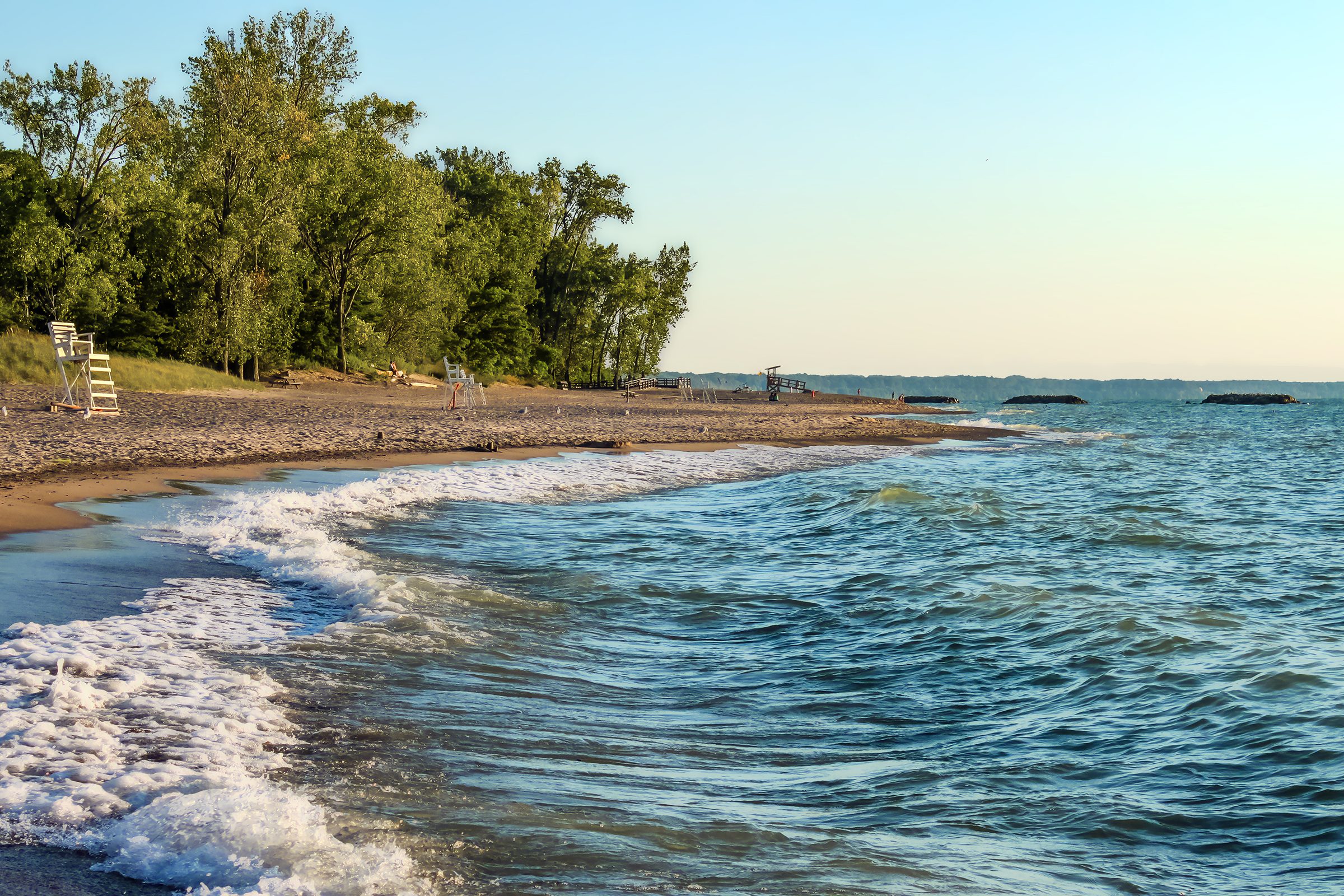 Deserted beach with lifeguard chairs and trees in background on Presque Isle on Lake Erie 