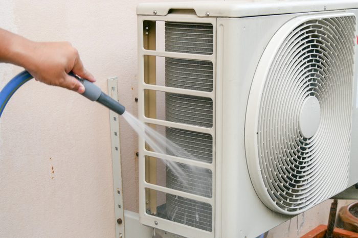 The men are cleaning the air conditioning condenser