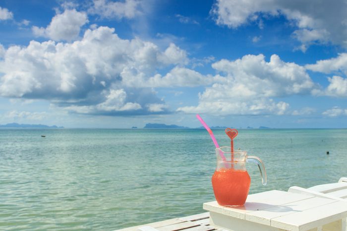 Red cocktail on white table set over ocean