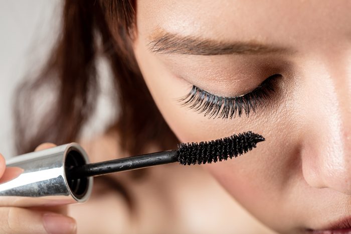 Woman applying mascara on eyelashes with makeup brush