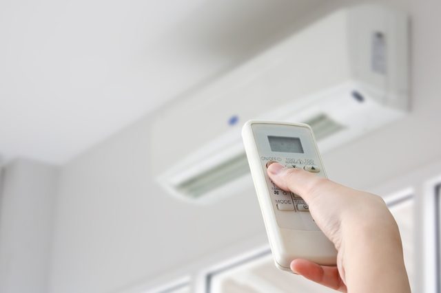 Hand with remote control directed on air conditioner
