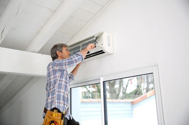 Repairman fixing air conditioner unit