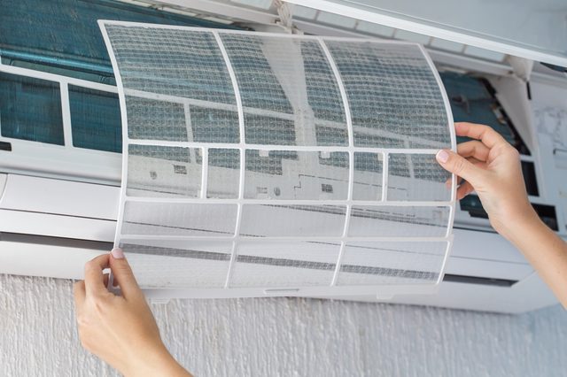 Dirty filter of air conditioner in female hands. Cleaning and washing maintenance