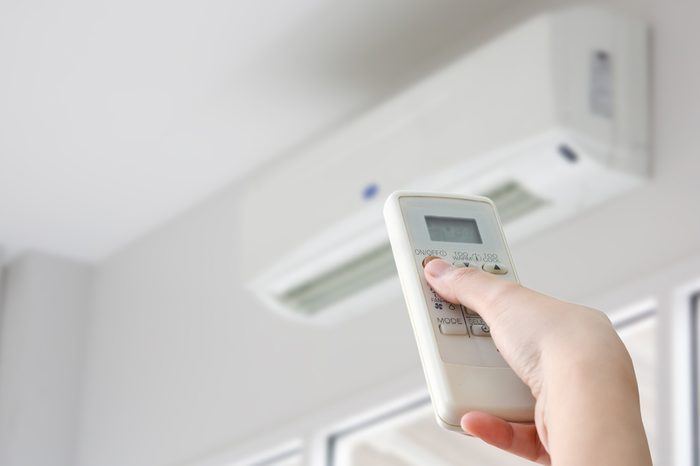 Hand with remote control directed on air conditioner