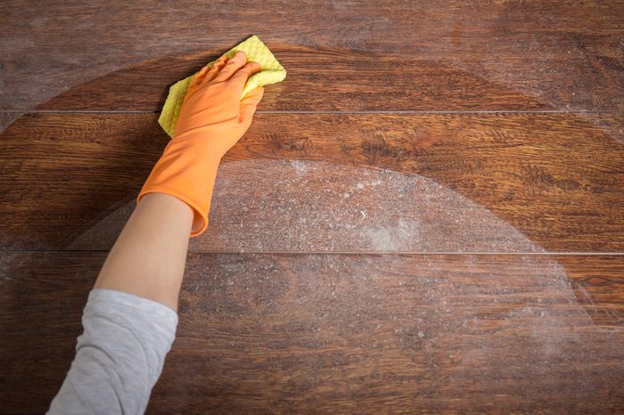 Close-up of hand cleaning wooden table with dishrag