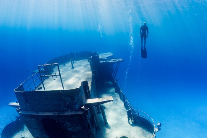 Freedivers swimming through a large underwater shipwreck