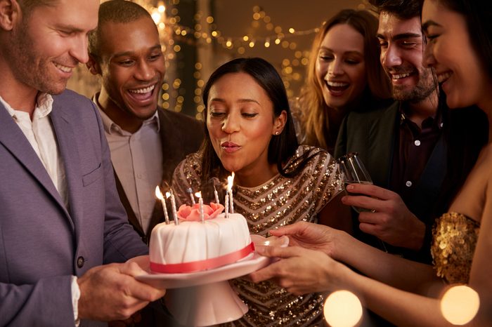Woman Blowing Out Candles On Birthday Cake