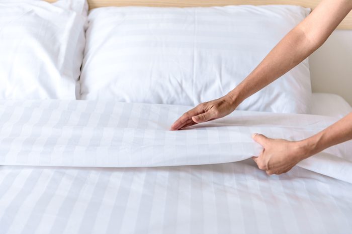 Hand set up white bed sheet in room