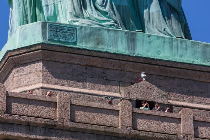 NEW YORK CITY, USA – JULY 15, 2013: A tourist at the foot of the Statue of Liberty on the observation deck while visiting the museum on a summer sunny day.