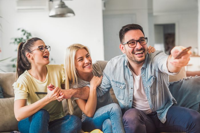Three friends relax and watch television in bright living room