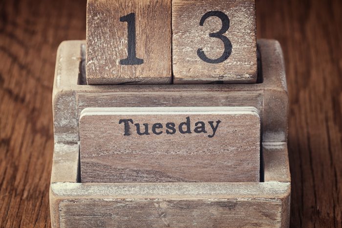 Grunge calendar showing Tuesday the thirteenth on wood background