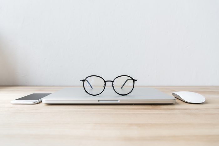 folded laptop at workplace with eyeglasses, smartphone and mouse