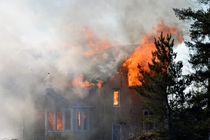 Old wooden house burning with lots of flames and smoke.