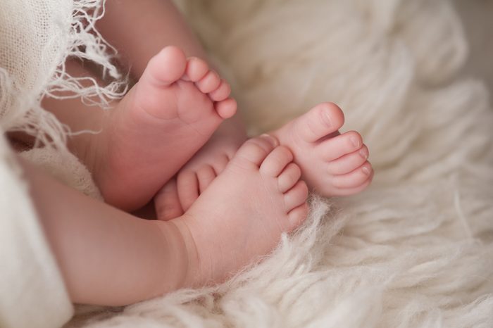 A closeup shot of the feet of twin girl babies. Shot in the studio on a sheepskin rug.