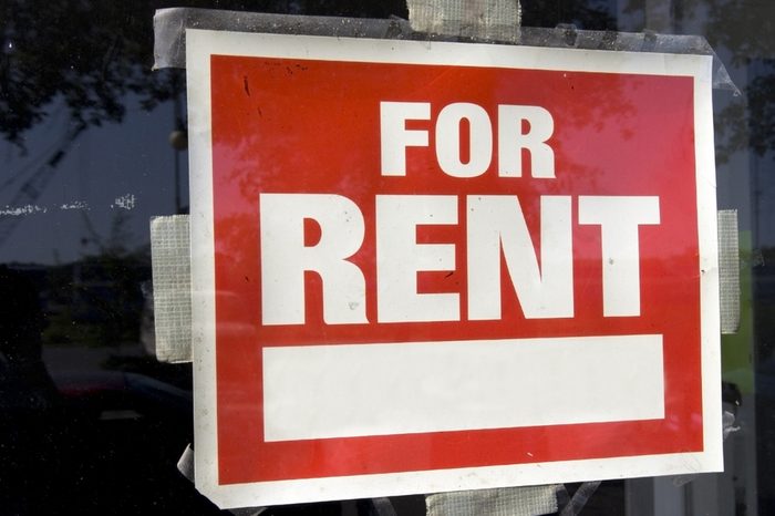 Red and white For Rent Sign taped to inside of window. Horizontal.