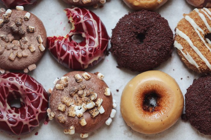 A 'from above' view of some gourmet donuts with a bite taken.