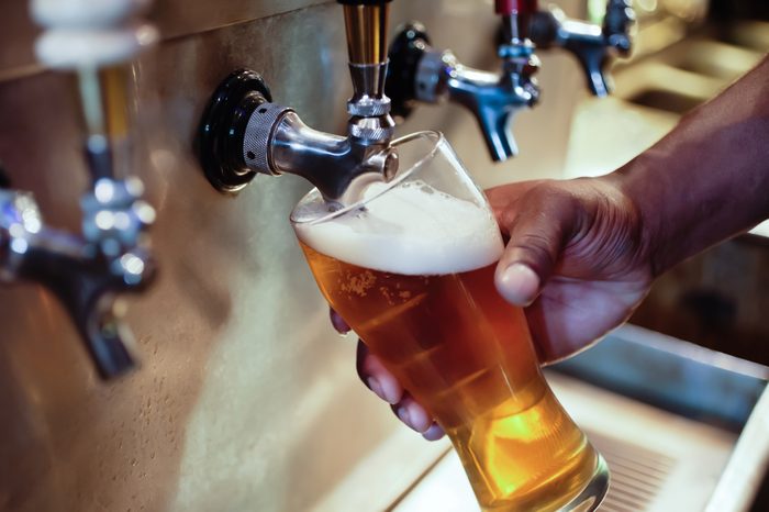 African American bartender filling beer glass from a bar tap