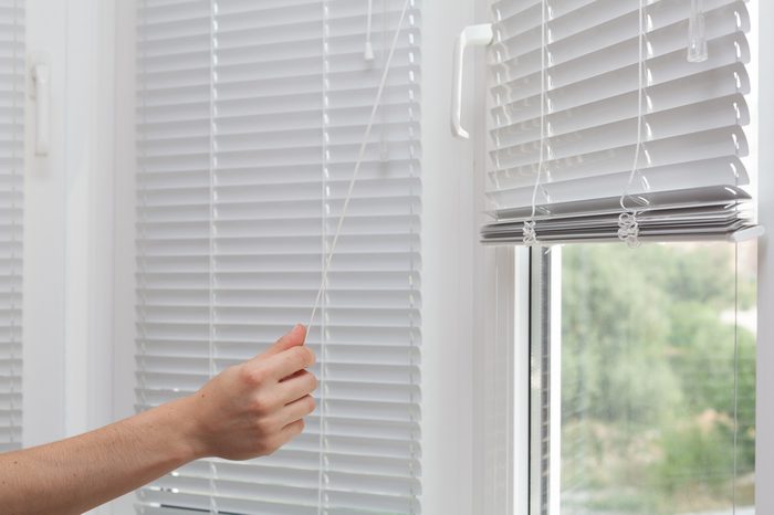 Girls hand raise the white blinds with a cord