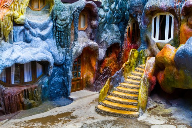 Colorful, sculpted building features winding stairs with vibrant textures, surrounded by windows embedded in a cave-like exterior.