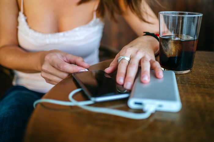 Close-up of Woman's hands plugging a mobile phone into a portable charger in a bar