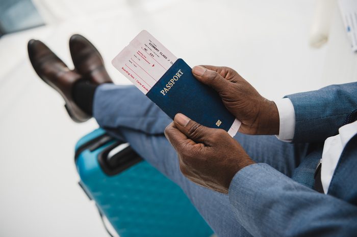 Cropped image of African american man holding passport and fly ticket in hands