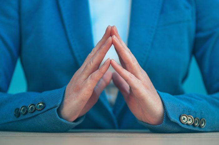 Steepled fingers of business woman as hand gesture sign of confidence, self-esteem, power and domination.