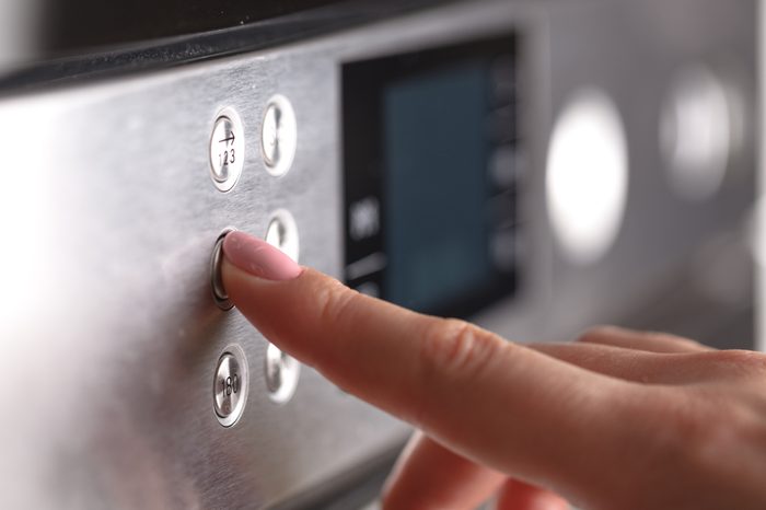 Close up female hand while using the microwave in her kitchen