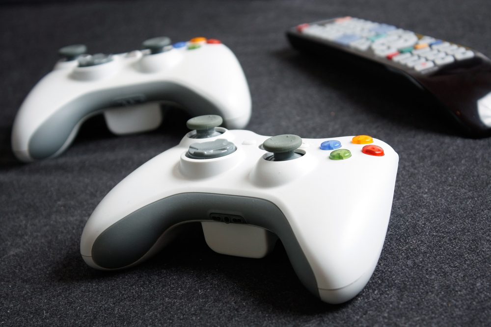 White game controllers lie on a dark fabric surface with a remote control in the background.