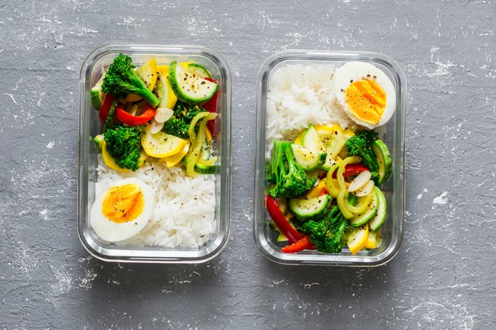 Vegetarian lunch box - stewed vegetables, rice and boiled egg on a gray background, top view. Health food concept