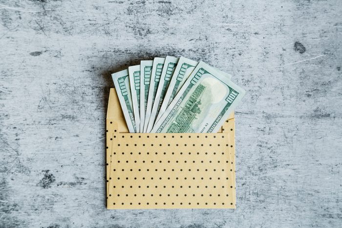 Desktop flatlay: the envelope with one hundred dollars bills lying on gray marble background