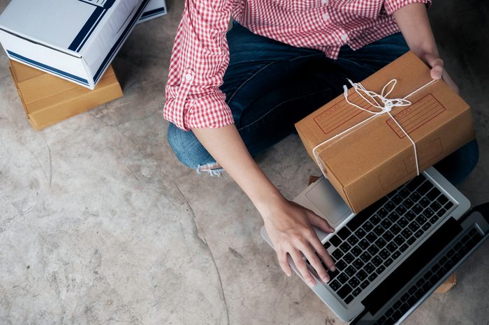 Young business start up online seller owner using computer for checking the customer orders from email or website and preparing packages for product office equipment. 