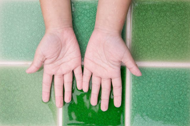 Hands are resting open on glossy, green, tiled surface.