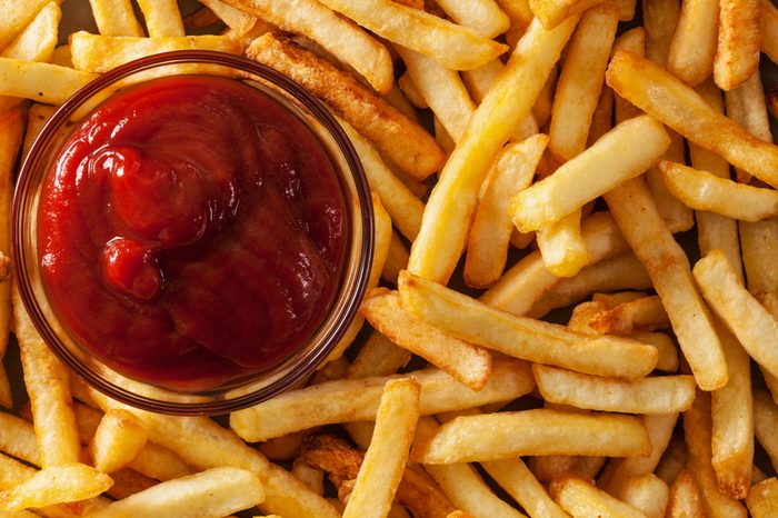 Delicious french fries and ketchup - fast food background, top view, closeup