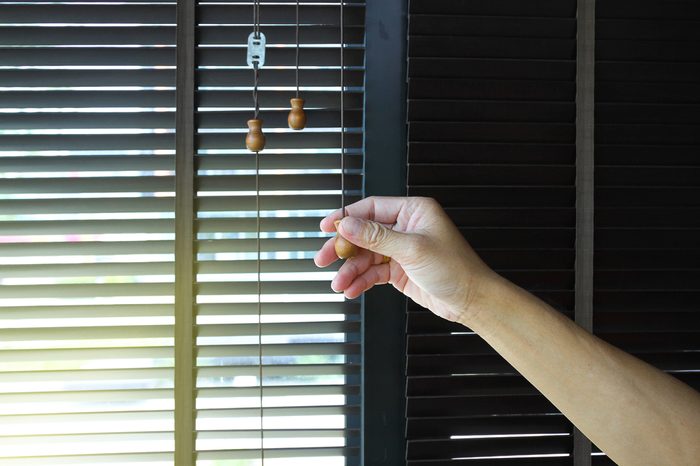 Man hand holding a wooden blinds decoration in livingroom
