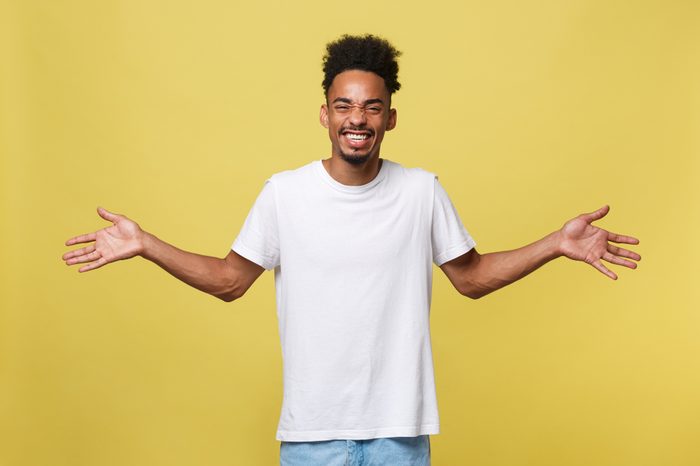 Advertising concept. Portrait of handsome African entrepreneur or office worker wearing suit pointing his finger at yellow studio wall with copy space for your content, looking shocked and surprised.