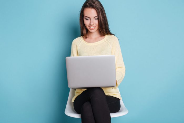 Smart beautiful young girl using laptop pc computer isolated on blue background