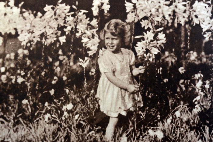 VARIOUS Princess Elizabeth later Queen Elizabeth II, as a child, gathering flowers in a garden, 1930.