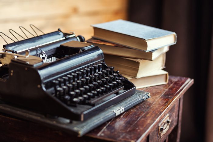 vintage typewriter and books on the table with blank paper on wooden desk