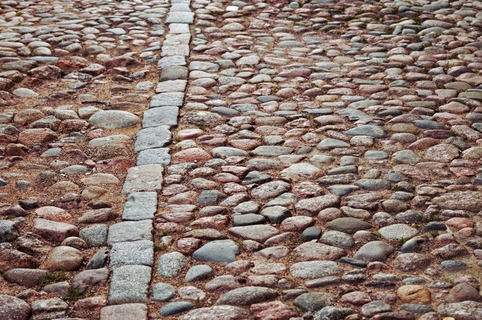 Cobblestone road. Large stones on road. Background from big stones. Road surface. Texture of stones. Selective focus.