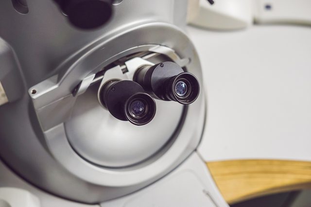 Binocular microscope lenses facing forward in a laboratory setting.