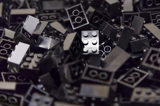 Black LEGO bricks piled together, some reflecting light, creating a shiny, intriguing texture.