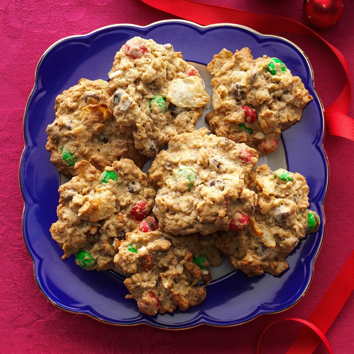 Cookies resting on a blue plate, filled with colorful candies, atop a red tablecloth with a ribbon nearby.