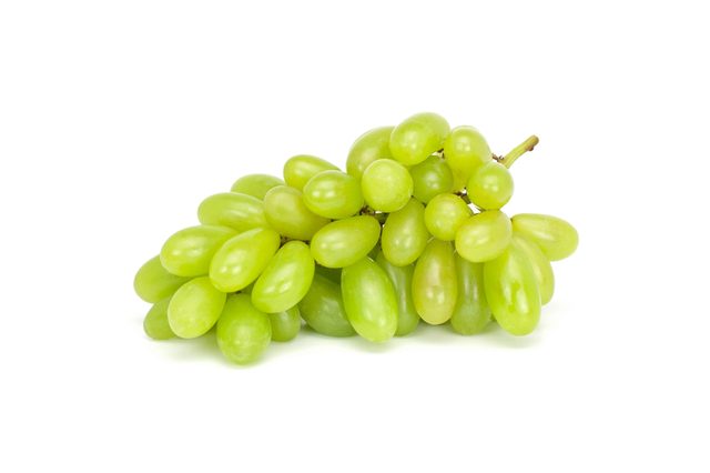 A bunch of green grapes lies together against a plain white background.