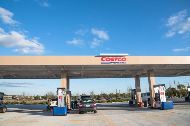 Gasoline pumps stand inactive; cars park beneath Costco canopy, surrounded by open sky.
