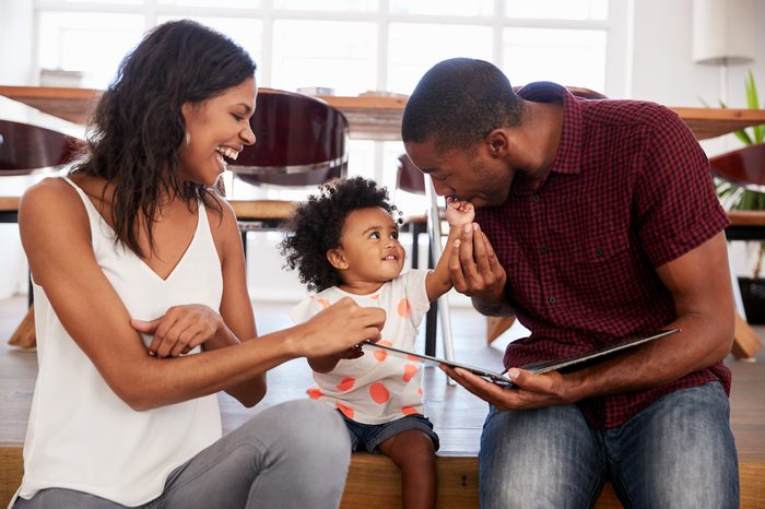 Parents Sitting And Reading With Daughter At Home