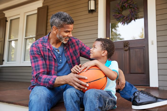 Father And Son Discussing Basketball On Porch Of Home