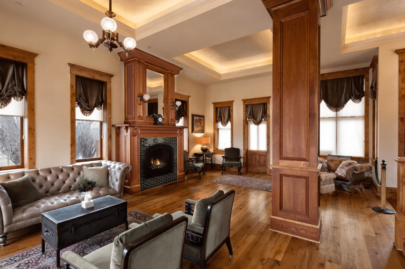 Fireplace warms elegant room; wooden interior, plush sofas, vintage decor create cozy atmosphere.